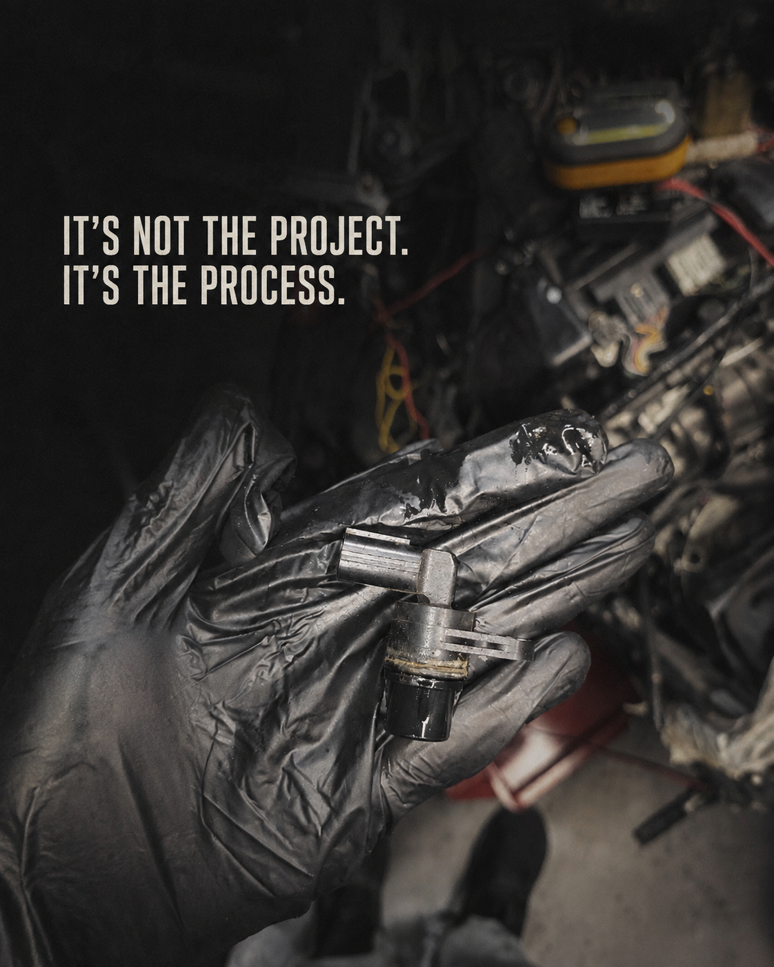 Gloved hand holding automotive parts during a repair
